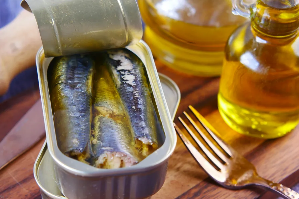 Boîte de sardines ouverte sur une table en bois